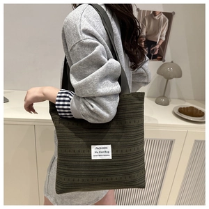 Détail du sac cabas en velours côtelé vert avec étiquette mode blanche et sangle souple
