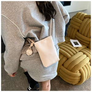 Détail du mini sac bandoulière en cuir crème avec bandoulière corde et charm pompon rond