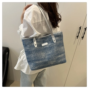 Detail of blue denim tote bag with silver metallic straps and rivet decorations