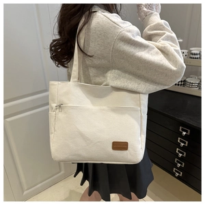 Detalle de bolso tote de lona con bolsillo frontal de cremallera y etiqueta de cuero