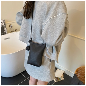 Détail du petit sac à bandoulière en cuir noir grainé avec une fine bandoulière à nœuds