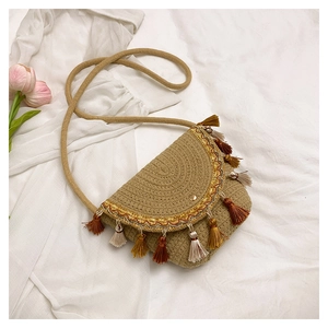 Detail of bohemian straw saddle bag featuring colorful tassels and ethnic embroidery