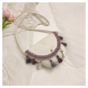 Detail of bohemian straw saddle bag with purple tassels and woven ethnic pattern trim
