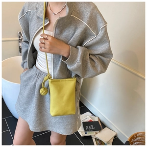 Détail du sac à bandoulière en cuir jaune avec nœud tressé et tenue de sport moderne