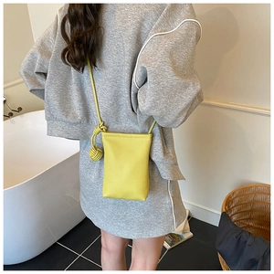 Détail d'un mini sac bandoulière jaune vif avec texture grainée et nœud sur la bandoulière
