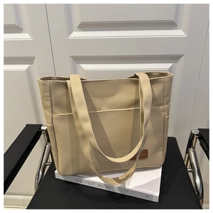 Detalle de las correas reforzadas y bolsillo exterior en un bolso tote beige
