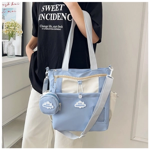Blue and white color-blocked nylon tote bag with round pouch shown on a model