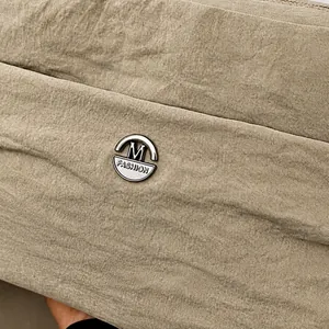 Macro detail of khaki messenger bag fabric texture with silver M FASHION metal logo