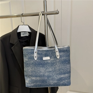 Blue glitter denim tote bag with silver chain strap and metal logo on office door