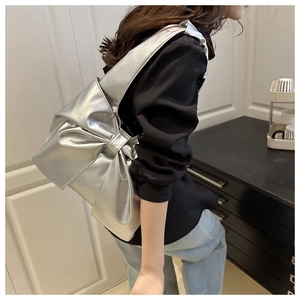 Détail d'un sac cabas argenté métallisé avec un grand nœud décoratif sur le devant