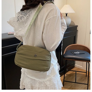 Olive green crossbody square bag featuring a round metal M logo and woven strap