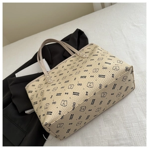 Close-up of beige tote bag showing litchi grain texture and cartoon bear pattern