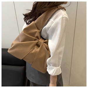 Détail d'un sac à épaule en similicuir marron orné d'un grand nœud décoratif chic