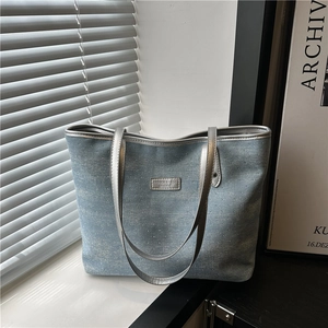 Blue denim tote bag with rhinestones and silver leather handles on white windowsill