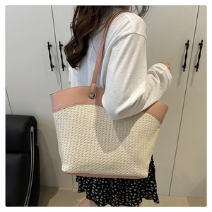 Detail view of woven straw tote bag with pink leather trim and metal ring strap connectors