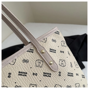 Close-up of litchi grain beige tote bag with cute cartoon bear prints and gold rivets