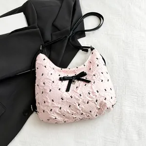 Dettaglio borsa rosa con trama a bolle, fiocco nero e ciondolo a cuore argentato