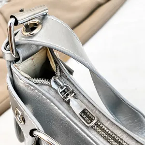 Detailopname van de gladde zilveren rits en metalen gesp op een retro halve maan tas