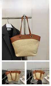 Close-up of a large woven straw tote with khaki brown trim and long shoulder straps