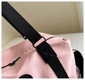 Detailed close-up of reinforced stitching and durable hardware on a pink travel duffel bag