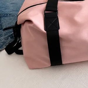 Detail shot of reinforced X-shape stitching on a pink nylon travel bag shoulder strap