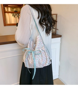 Floral print shoulder bag with bow detail showing back view on model for style