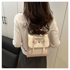 Détail du sac à dos avec nœud décoratif, pendentif cœur et rabat en similicuir rose