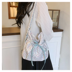 Detail of floral drawstring bucket bag showing canvas texture and blue checkered bow