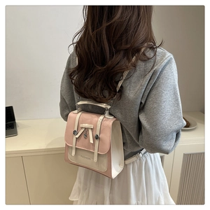 Détail du sac à dos rose et beige avec pendentif papillon et boucle en métal chic