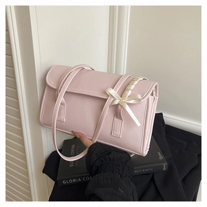 Detalle del bolso de hombro rosa claro con lazo crema y silueta rectangular elegante