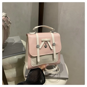 Détail d'un sac à dos bicolore rose et blanc avec nœud et pendentif en métal en cœur