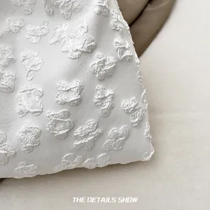 Detailed view of white canvas bag featuring 3D butterfly embroidery and lace texture