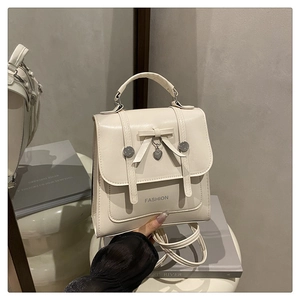 Détail d'un sac à dos en similicuir crème avec nœud et pendentif cœur argenté