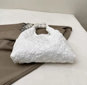 Detailed close-up of 3D floral texture and lace pattern on white canvas shoulder bag