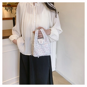 Detailed shot of floral handbag with white lace trim and purple blossom print