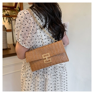 Macro shot of brown woven straw texture and gold geometric metal lock on a shoulder bag