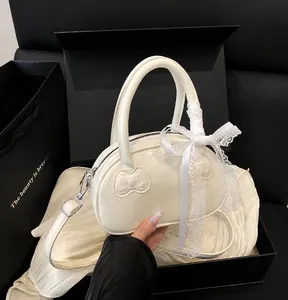 Detailed view of cream-white patent leather handbag with lace bow in a premium gift box