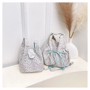 Detail of floral bucket bag featuring white lace trim and green plaid drawstring bow