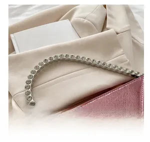 Detailansicht der rosa Metall-Herz-Tasche mit Strass-Griff auf einem weichen Blazer