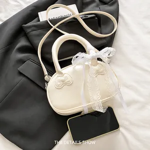 Detail of cream small square bag with decorative lace bow and butterfly embossed pattern