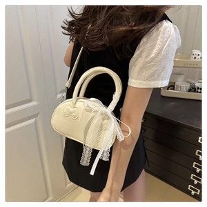 Cream white handbag with bow pattern and lace ribbon decoration on a female model