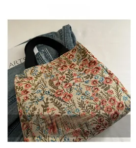 Detail of floral jacquard tote bag with vibrant patterns and black top handles