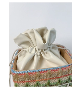 Détail d'un sac seau en paille tissé main avec cordon en cuir crème et texture colorée
