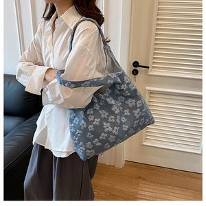 Dettaglio borsa tote in tela blu con applicazioni floreali 3D e ampia capacità interna