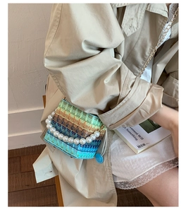 Détail du sac seau tissé arc-en-ciel avec anse en perles et bandoulière dorée