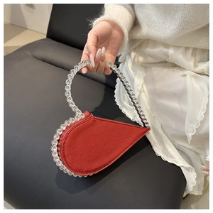 Detail einer roten herzförmigen Satin-Abendtasche mit funkelnden Strass-Verzierungen
