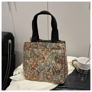 Detailed view of floral jacquard fabric and black woven handles on retro shoulder tote bag