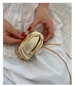 Détail d'un sac de soirée ovale en métal doré brillant avec bandoulière chaîne
