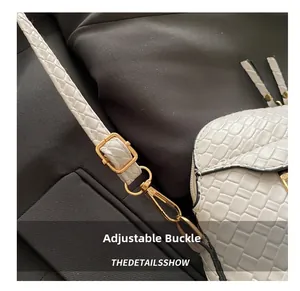 Detail of white woven shell bag showing adjustable gold buckle and premium texture