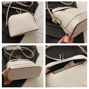 Detail view of white shell bag with crocodile texture, gold zippers and inner pocket